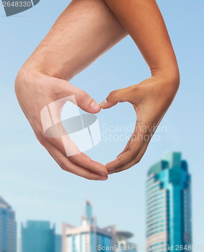 Image of woman and man hands showing heart shape