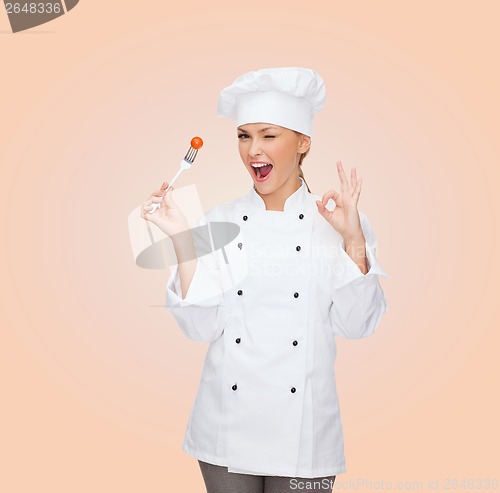 Image of smiling female chef with fork and tomato