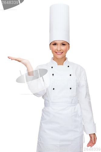 Image of smiling female chef holding something on hand