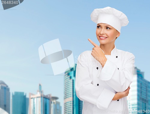 Image of smiling female chef pointing finger to sonething