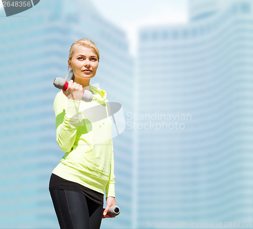 Image of sporty woman with light dumbbells outdoors