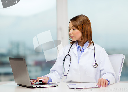 Image of busy doctor with laptop computer and clipboard