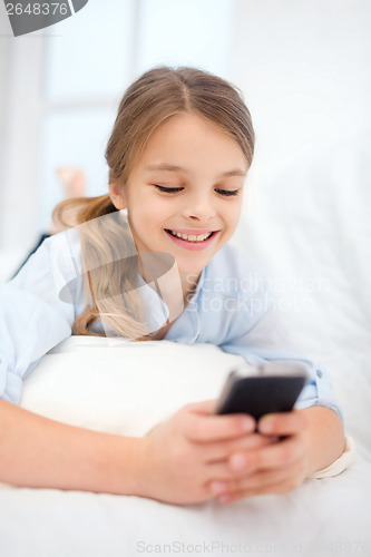 Image of smiling girl with smartphone at home