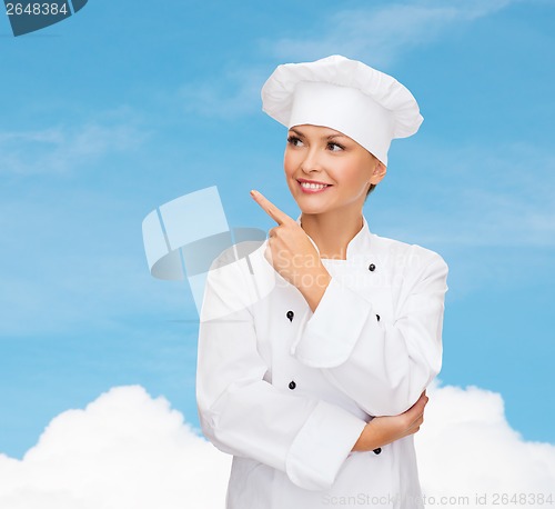 Image of smiling female chef pointing finger to sonething