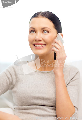 Image of smiling woman with smartphone at home