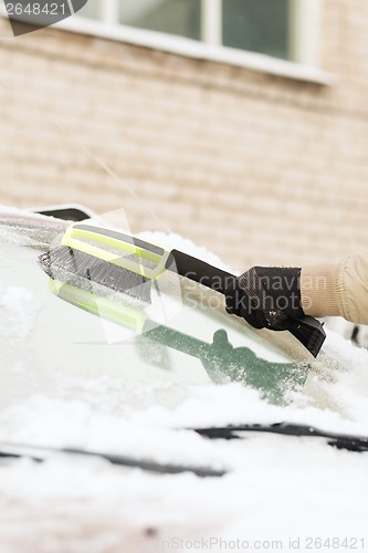 Image of closeup of man cleaning snow from car