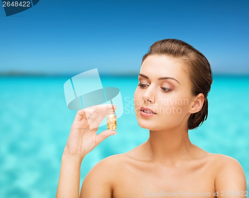 Image of beautiful woman showing bottle with golden dust