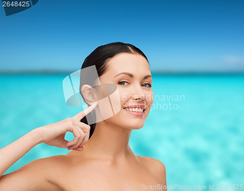 Image of young calm woman pointing to her ear