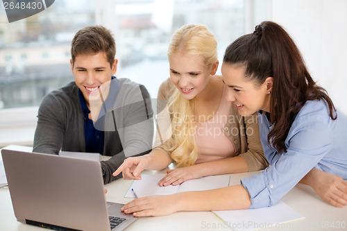 Image of three smiling students with laptop and notebooks