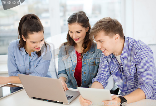 Image of three smiling students with laptop and tablet pc