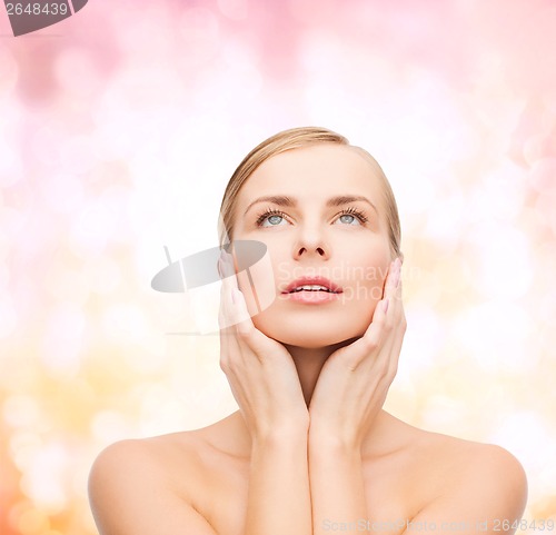 Image of beautiful woman touching her face and looking up