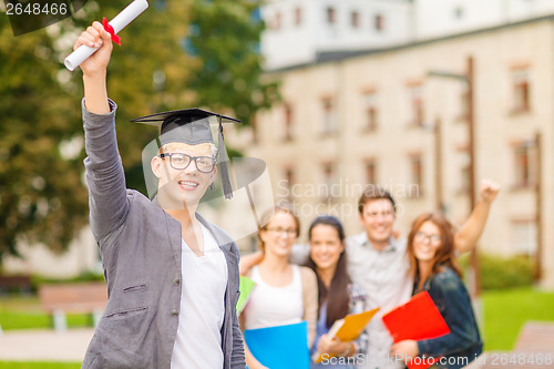 Image of smiling teenage boy in corner-cap with diploma