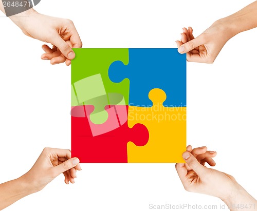 Image of four hands connecting puzzle pieces