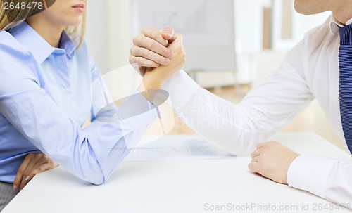 Image of businesswoman and businessman arm wrestling