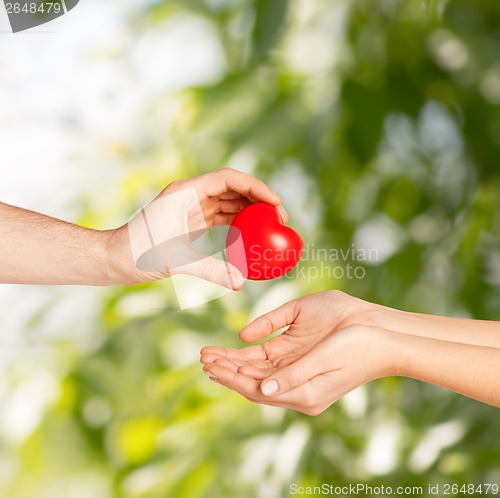 Image of man hand giving red heart to woman