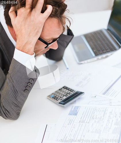 Image of businessman with papres, laptop and calculator