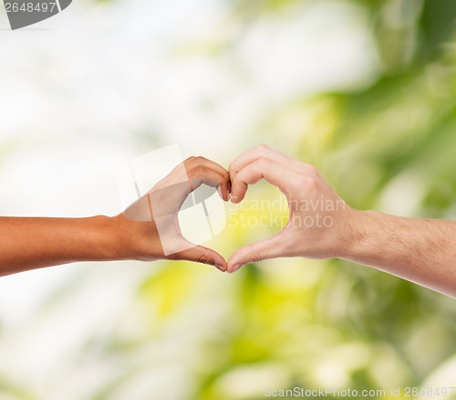 Image of woman and man hands showing heart shape