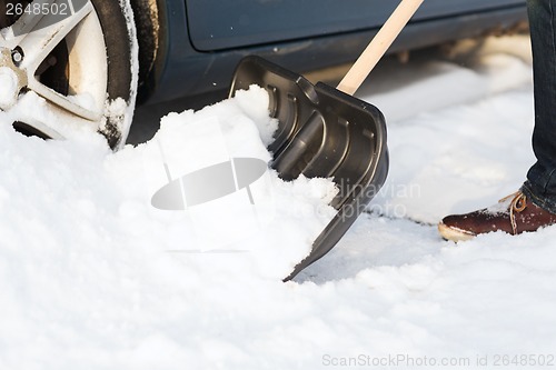 Image of closeup of man digging up stuck in snow car