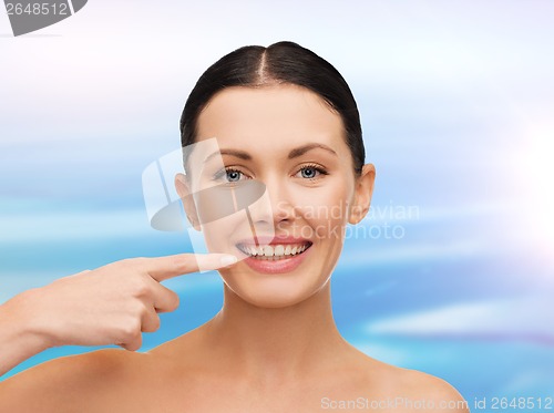 Image of young calm woman pointing to her mouth