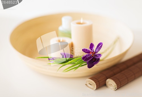 Image of candles and iris flowers in wooden bowel and mat