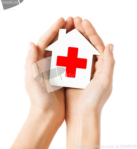 Image of hands holding paper house with red cross