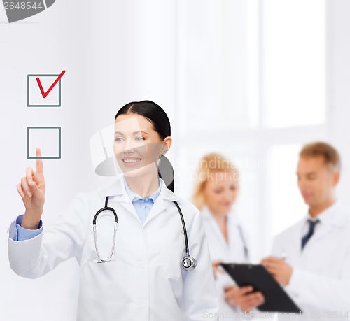Image of smiling female doctor pointing checkbox