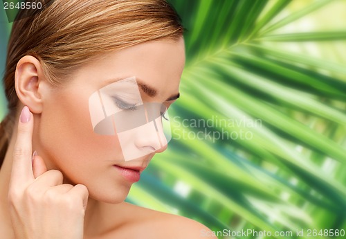 Image of calm woman touching her ear