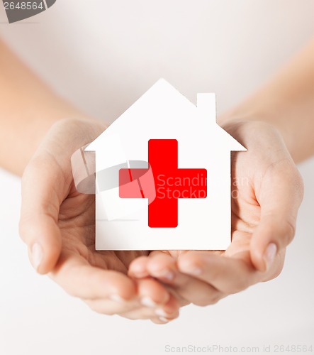 Image of hands holding paper house with red cross