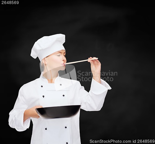 Image of smiling female chef with pan and spoon