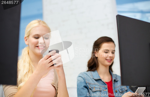 Image of two teens with smartphones in computer class