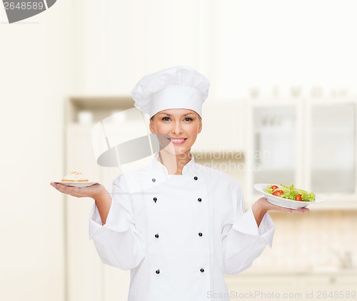 Image of smiling female chef with salad and cake on plates