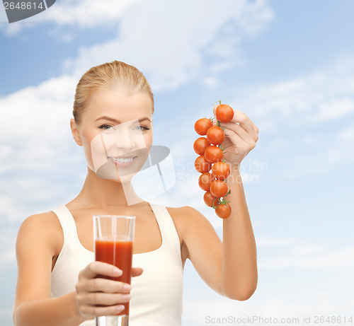 Image of woman holding glass of juice and tomatoes