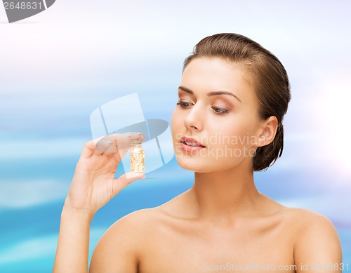 Image of beautiful woman showing bottle with golden dust