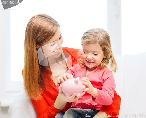 Image of happy mother and daughter with small piggy bank