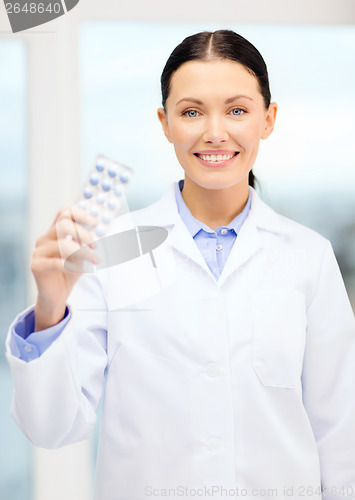 Image of smiling young doctor in cabinet with pills
