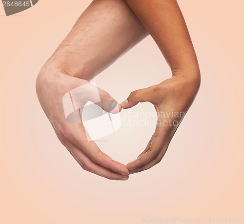 Image of woman and man hands showing heart shape
