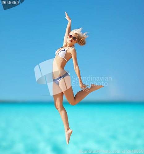 Image of happy woman jumping on the beach