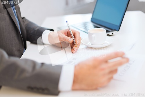 Image of man hands with contract and pen, coffee and laptop