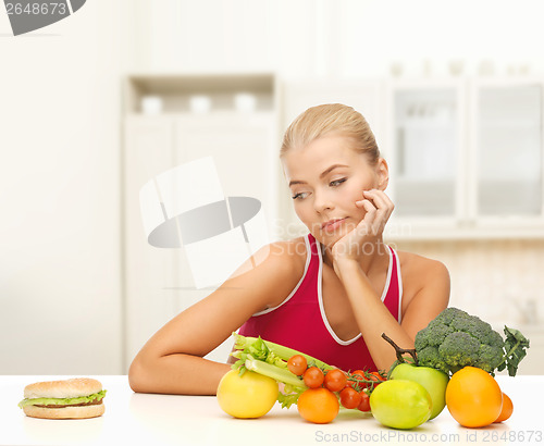 Image of doubting woman with fruits and hamburger