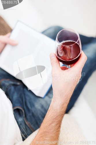 Image of male hand holdind book and glass of red wine