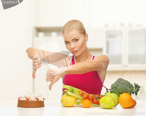 Image of woman with fruits showing thumbs down to cake