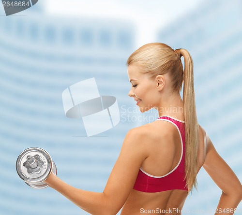 Image of smiling woman with heavy steel dumbbell