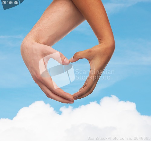 Image of woman and man hands showing heart shape