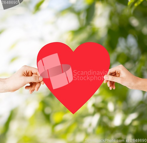 Image of couple hands holding red heart