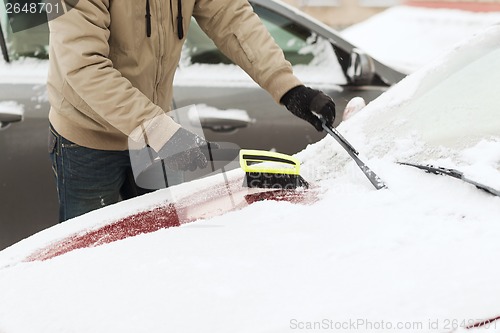 Image of closeup of man cleaning snow from car