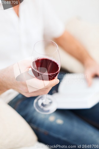 Image of male hand holdind book and glass of red wine