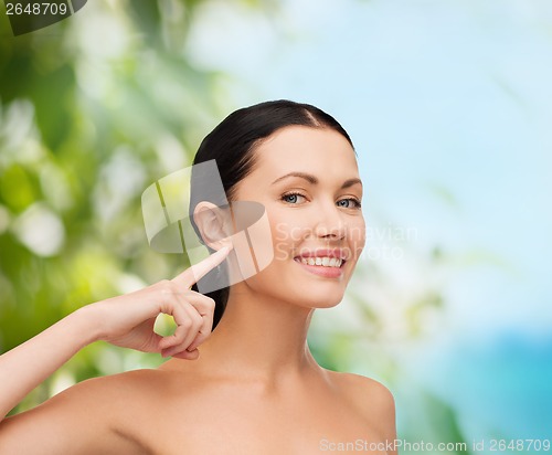 Image of young calm woman pointing to her ear