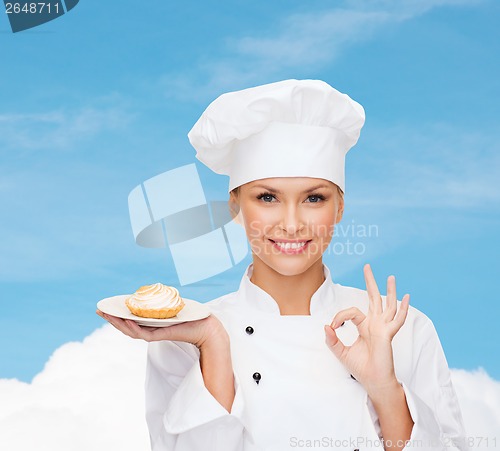 Image of smiling female chef with cake on plate