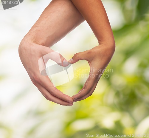 Image of woman and man hands showing heart shape