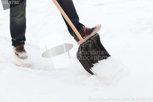 Image of closeup of man shoveling snow from driveway